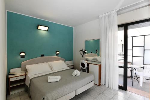 里米尼Hotel Criniera D'oro的一间卧室配有一张床铺和一张桌子,还有一间浴室