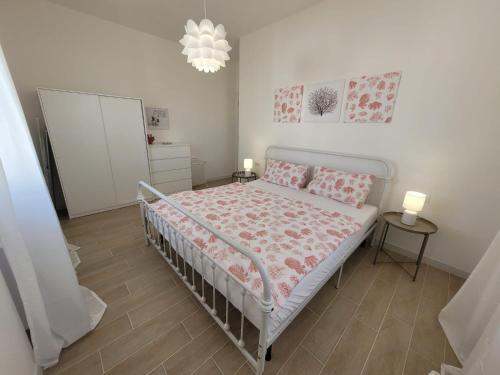 丽都玛里尼Appartamento Demetrio 50m mare & shopping的白色卧室配有带粉红色床单的床