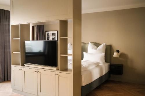 韦斯特兰Mimosa Hotel的一间卧室配有电视和一张带白色枕头的床。