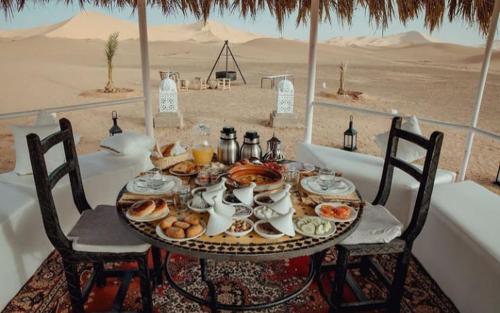伊尔富德Merzouga dreams Camp的一张桌子,上面有食物在沙漠里