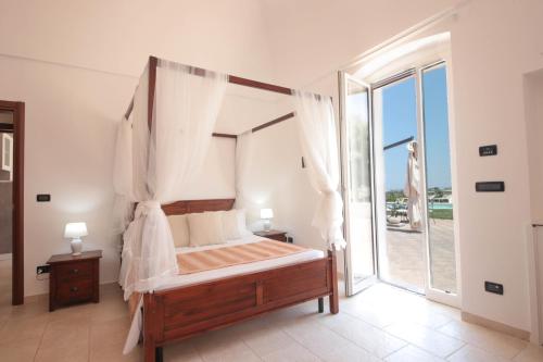 莫诺波利Villa Dyria exclusive swimming pool的一间卧室设有一张天蓬床和大窗户