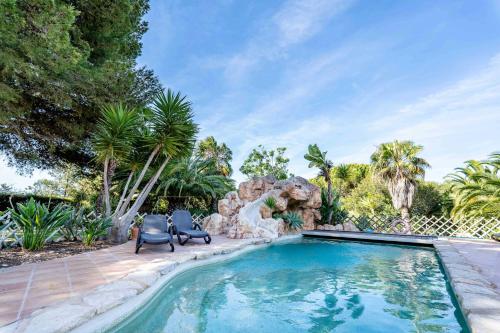 贝纳吉Villa Concha by Indigo的庭院内的游泳池,配有两把椅子和树木