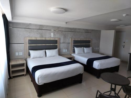 谢普斯敦港Bayside Taj Hotel的酒店客房设有两张床和一张桌子。