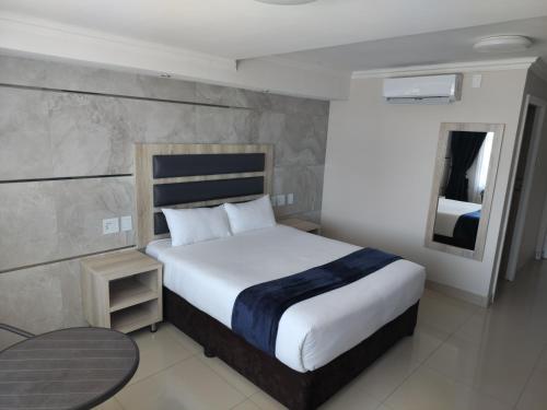 谢普斯敦港Bayside Taj Hotel的一间卧室配有一张床、一张桌子和一面镜子