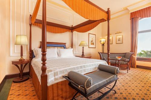 加尔各答欧贝罗伊大加尔各答酒店的一间卧室配有一张天蓬床和一把椅子