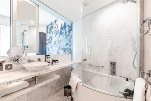 迪拜第一媒体酒店的一间带水槽、浴缸和镜子的浴室