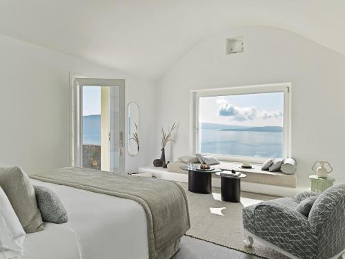 伊亚Canaves Oia Suites - Small Luxury Hotels of the World的一间卧室配有一张床、一张沙发和一个窗口