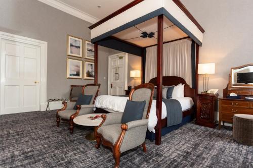 爱丁堡皇家苏格兰俱乐部酒店的酒店客房设有天蓬床和椅子