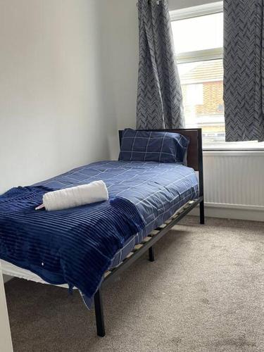 彼得伯勒Ideal Location for Work/Fun/Food/Holidays/Gym的一间卧室配有一张带蓝色床单的床和一扇窗户。
