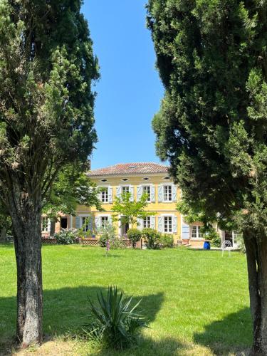 AzasVilla Toscane - Atelier d'Artistes et B&B à 20 mn de Toulouse的一座大黄色房子前面有树木