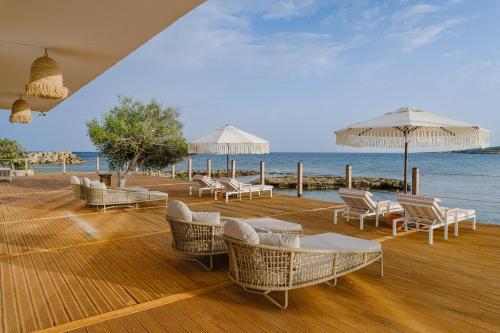 RizokarpasoBlue Sea Karpasia Hotel的海滩上带椅子和遮阳伞的木制甲板