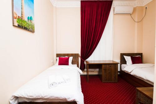 布哈拉Boutique hotel Shakh的一间设有两张床和红地毯的客房