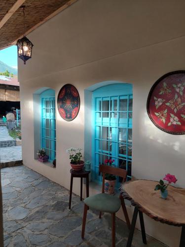 舍基Guest House Ruh Achari的一间设有蓝色窗户和桌椅的客房