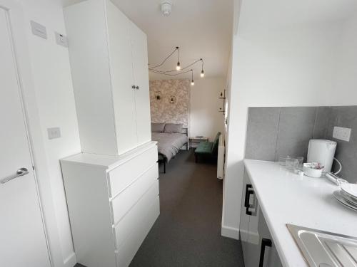 伦敦Cosy Bright Studio Apartment Close to Wembley Stadium的一间带水槽的白色厨房和一间卧室