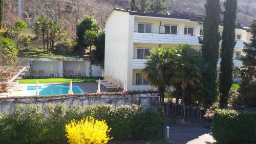 梅拉诺迈克西米利安酒店的一座白色的大建筑,设有游泳池和树木