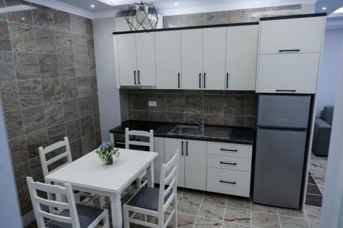 维利波吉Fishta apartments Q5 35的厨房配有白色橱柜和白色的桌椅