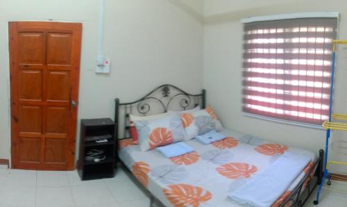 巴西富地Adilah Homestay A的一间卧室配有带橙色和白色枕头的床