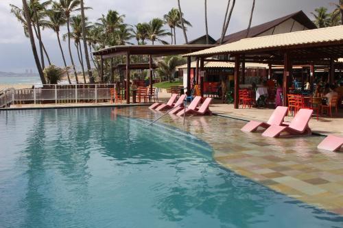 纳塔尔Vila do Mar Natal - All Inclusive的游泳池,游泳池内摆放着粉红色的躺椅