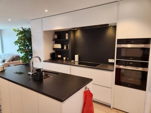 克诺克－海斯特Appart Noah SeaFront的厨房配有白色橱柜和黑色台面