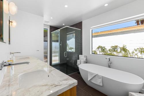 棕榈泉Desert Orchid Retreat的一间带大型白色浴缸和大窗户的浴室