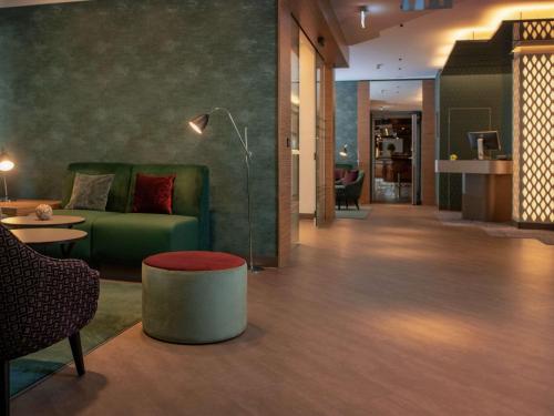 科隆美居科隆贝佛斯特拉瑟酒店的客厅配有绿色沙发和桌子