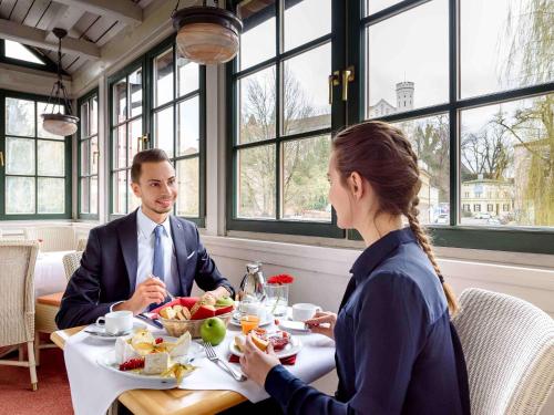 弗赖辛慕尼黑机场弗莱辛美居酒店 的坐在餐桌旁吃食物的男人和女人