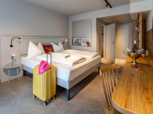 格拉茨ibis Styles Graz Messe的一间卧室配有一张大床和一个黄色的行李箱