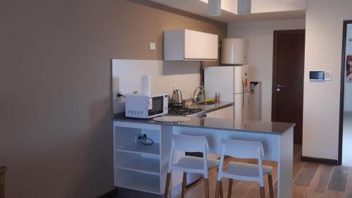 巴拉那MONOAMBIENTE - Parana TU CASA的厨房配有带2把椅子的柜台和冰箱。
