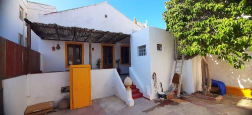 法鲁Hostel A Casa da Árvore的白色的房子,有黄色的门和一棵树