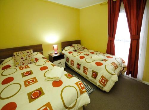 塔尔卡Alojamientos San Sebastián Talca的一间卧室设有两张床和窗户。