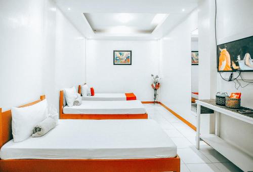 黎牙实比RedDoorz S&L Apartelle Daraga Albay的白色客房的两张床,拥有橙色色调