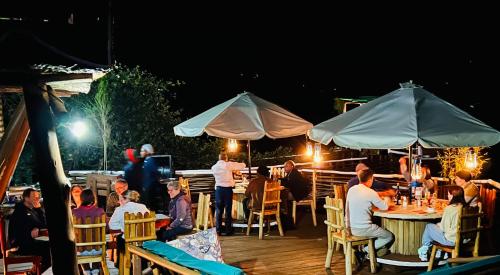 卡巴莱Lake Bunyonyi Rock Resort的一群人晚上坐在甲板上的桌子上