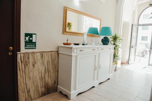 布林迪西都灵酒店的一间带镜子和白色橱柜的浴室