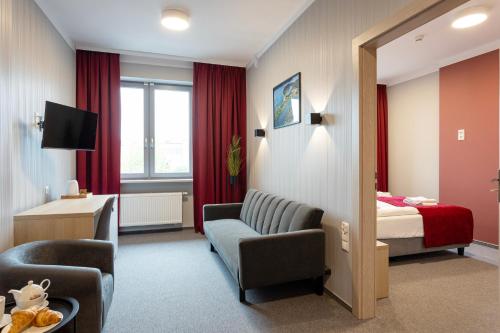 奥古斯图Apartamenty Albatros的酒店客房配有床、沙发和椅子