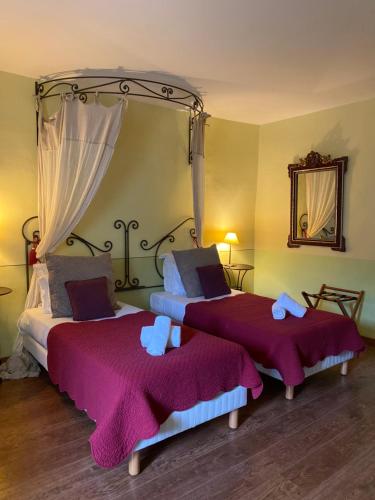 MaubecLa Bastide Du Bois Breant的一间卧室配有两张带紫色毯子和镜子的床