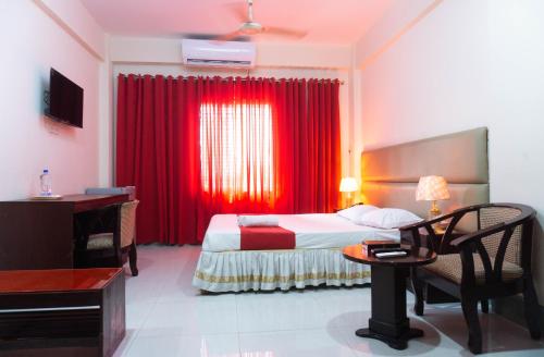 吉大港Hotel Golden Inn Chattagram Ltd的酒店客房,配有床和红色窗帘