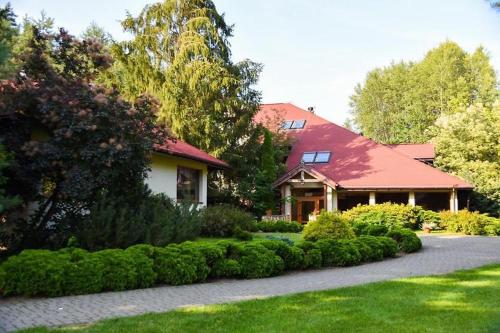 ZabłudówBobrowy Resort的一座有红色屋顶和灌木的房子