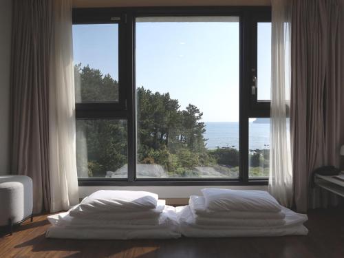 西归浦市Hotel Seogwipean的卧室设有2张床,位于大窗户前