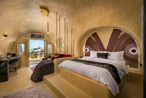 费拉Canyon Santorini的一间大卧室,配有一张大床和拱形天花板