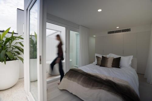 悉尼The Manly House - 100 steps from Manly Beach的女人在卧室里走着,卧室里有床