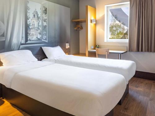 瑟松塞维涅B&B HOTEL Rennes Est Cesson Sévigné的酒店客房设有两张床和窗户。