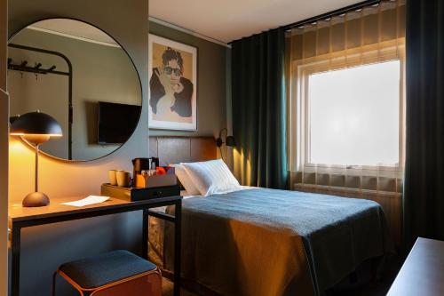哥德堡斯巴尔加尔达酒店的一间卧室配有一张床、一张书桌和一面镜子
