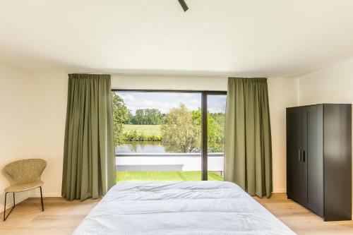 代因泽Leie Villa II - by the river with sauna & jacuzzi的一间卧室设有一张床和一个大窗户