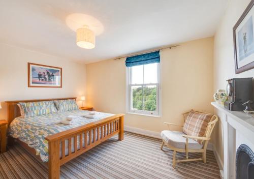 金斯韦尔Oystershell Cottage的一间卧室设有一张床、一个窗口和一把椅子