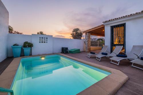 阿尔布费拉Villa Belize by Algarve Vacation的一个带椅子和房子的庭院内的游泳池