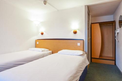 韦克菲尔德钟楼韦克菲尔德酒店的配有白色墙壁的小客房内的两张床