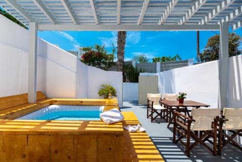卡特瑞杜斯Aerenia Luxury Suites的庭院设有游泳池和桌椅