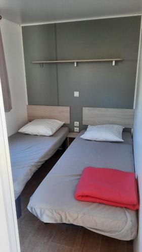 纳博讷普拉日MobilHome de Charlotte - Camping La Falaise 4 étoiles的宿舍间内的两张床,上面有红毯