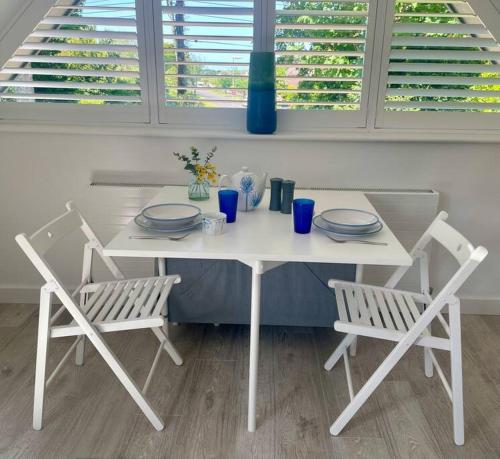 滨海巴顿Cosy accommodation, easy walk to beach!的一张带两把椅子的白色桌子和一张带盘子的桌子
