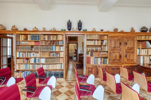 洛迦诺Villa by @ Home Hotel Locarno的图书馆配有红色椅子和木制书架
